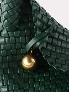 Sac à main vert en cuir tissé, élégant sac porté épaule avec pendentif boule dorée.