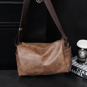 Detail shot of brown casual crossbody bag, soft leather texture, compact size for men.