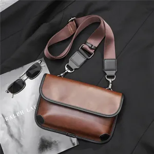 Detail shot of stylish brown pu leather messenger bag with adjustable strap and metal hardware.