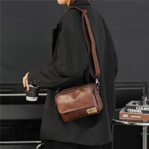 Detail shot of retro brown leather messenger bag worn crossbody, showing texture and strap.