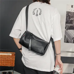 Detail shot of a black leather cylinder crossbody bag showcasing strap and zipper design.