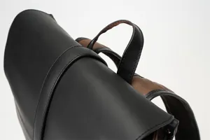 Detail shot of men's black vintage PU leather backpack with brown straps and top handle for daily use