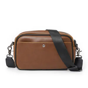 Vista dettagliata della borsa a tracolla in pelle PU marrone con cinturino nero e accessori scuri.