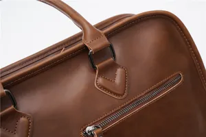 Close-up detail of brown leather business briefcase, showcasing zipper pocket and stitching.