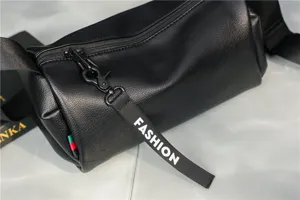 Detailed shot of black leather cylindrical crossbody bag with trendy strap and smooth zipper.