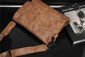 Detailed shot of brown vintage men's messenger bag with wide strap and metallic hardware.