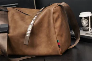 Brown PU leather travel duffel bag detail showcasing sturdy strap and textured surface.