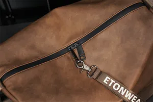 Detailed close-up view of the brown leather travel duffel bag featuring a strong black zipper.