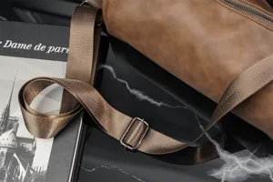 Dettaglio borsa a tracolla cilindrica, borsa casual marrone con cinghia regolabile.