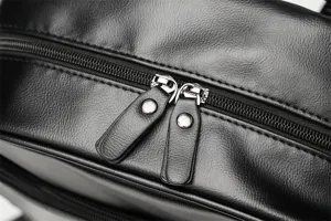 Primo piano della cerniera dello zaino in pelle nera con dettagli hardware resistenti.