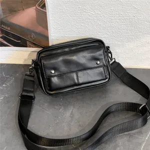 Black leather crossbody bag detail view, stylish men shoulder bag with wide strap and front pocket.