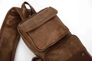 Detailed view of men brown leather sling bag with multi pockets and durable strap.