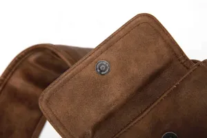 Close-up detail of the brown leather chest bag showing metallic magnetic snap hardware.