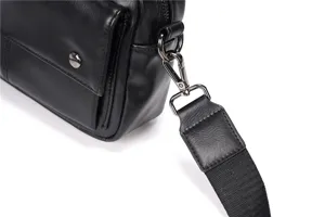 Detailed view of black leather crossbody bag strap and metal hardware buckle design.