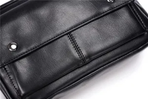 Black leather crossbody bag detail, premium textured fabric and metallic hardware close up