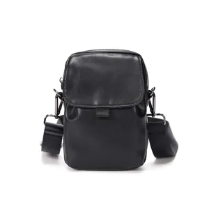 Detalle de un pequeño bolso bandolera negro de cuero sintético con herrajes metálicos.