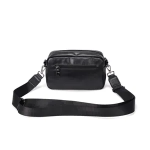 Black leather crossbody bag detail showcasing durable strap, smooth zipper, and compact shape.