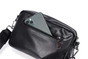 Close-up detail of black leather crossbody bag featuring front zipper pocket and metal hardware.