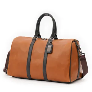 Brown leather travel duffel bag detail showing black handles, sturdy zippers and shoulder strap.