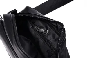 Black leather mens crossbody bag interior detail showing zipper pocket and fabric lining.