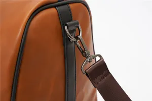 Close-up detail of a brown leather travel duffel bag strap hook and metal hardware piece.