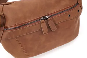 Gros plan détaillé sur le sac de poitrine marron pour homme, mettant en valeur la double fermeture.