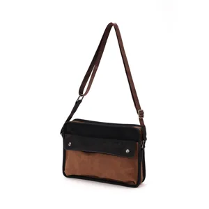 Detailed view of the brown and black spliced retro messenger bag strap and metal hardware.