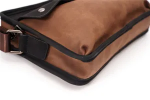 Detail shot of casual men's messenger bag with brown PU leather and black trim design.