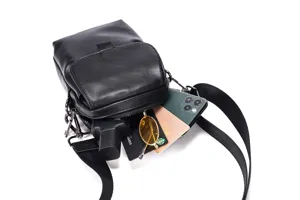Vista detallada del pequeno bolso cruzado negro que muestra la capacidad interna con movil.