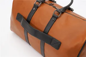 Close-up detail of a brown leather travel duffel bag with black straps and metal zippers.