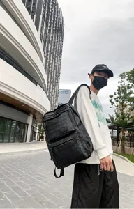 Dettaglio dello zaino in pelle intrecciata nera, stile urbano all'aperto, grande capacità.