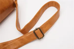 Close-up detail of the vintage brown faux leather crossbody bag strap with metal buckle.