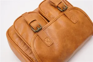Vintage brown faux leather crossbody bag detail featuring double front pockets and metal buckles.
