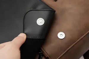 Close-up detail of retro PU leather backpack magnetic snap button and closure flap structure.