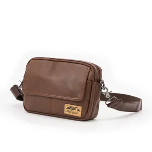 Detail view of the brown leather messenger bag featuring adjustable strap and metal hardware.