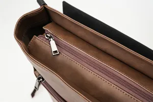 Close-up detail of retro brown PU leather backpack zipper and interior compartment structure.