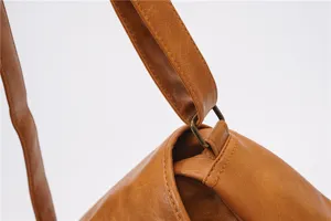 Close-up detail of vintage brown PU leather shoulder bag strap and metal ring hardware.