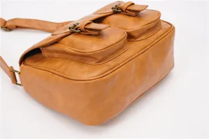 Retro leather messenger bag detail showing dual front pockets and durable bronze hardware.