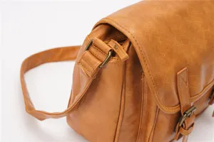 Detailed view of the vintage brown leather messenger bag, showing texture and classic retro hardware style.