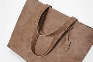 Detailed view of the stylish brown PU leather tote bag, showcasing fine texture and handles.