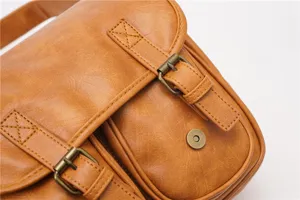 Detailed close-up view of vintage brown PU leather messenger bag buckle and strap texture.