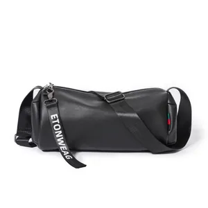 Close-up detail shot of the elegant black cylindrical crossbody bag with branded strap.