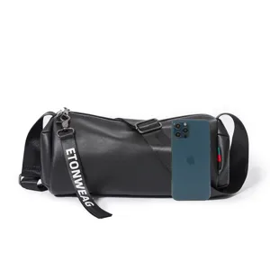 Detail view of black cylindrical shoulder bag with branded strap and smooth zipper closure.