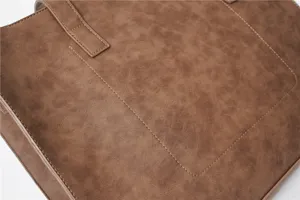 Close-up detail of brown PU leather tote bag showing fine stitching and premium texture.