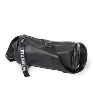 Black cylindrical shoulder bag detail showing premium leather texture and adjustable strap.
