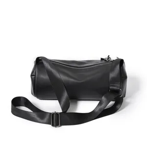 Black cylindrical barrel crossbody bag with adjustable wide strap for casual daily use.