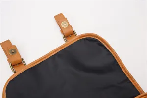 Brown leather bag detail view featuring metal magnetic snap closure and black lining.