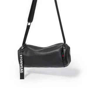 Black cylindrical shoulder bag detail, featuring durable PU leather, zipper closure and strap.