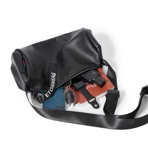 Detail view of black leather cylinder crossbody bag showing internal storage capacity.