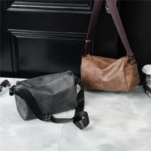 Cylindrical leather shoulder bag for men, casual crossbody design with wide strap detail.